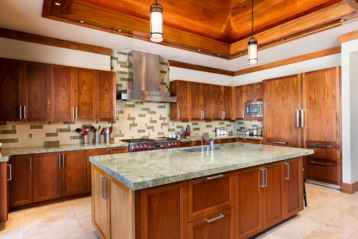 Kitchen with wood paneled cabinets, island and grill-hood over range