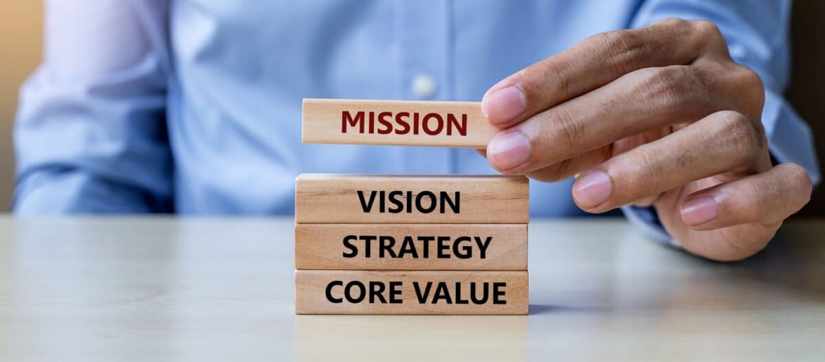 Hand holding building blocks that have the words mission, vision, strategy, and core values on them. 